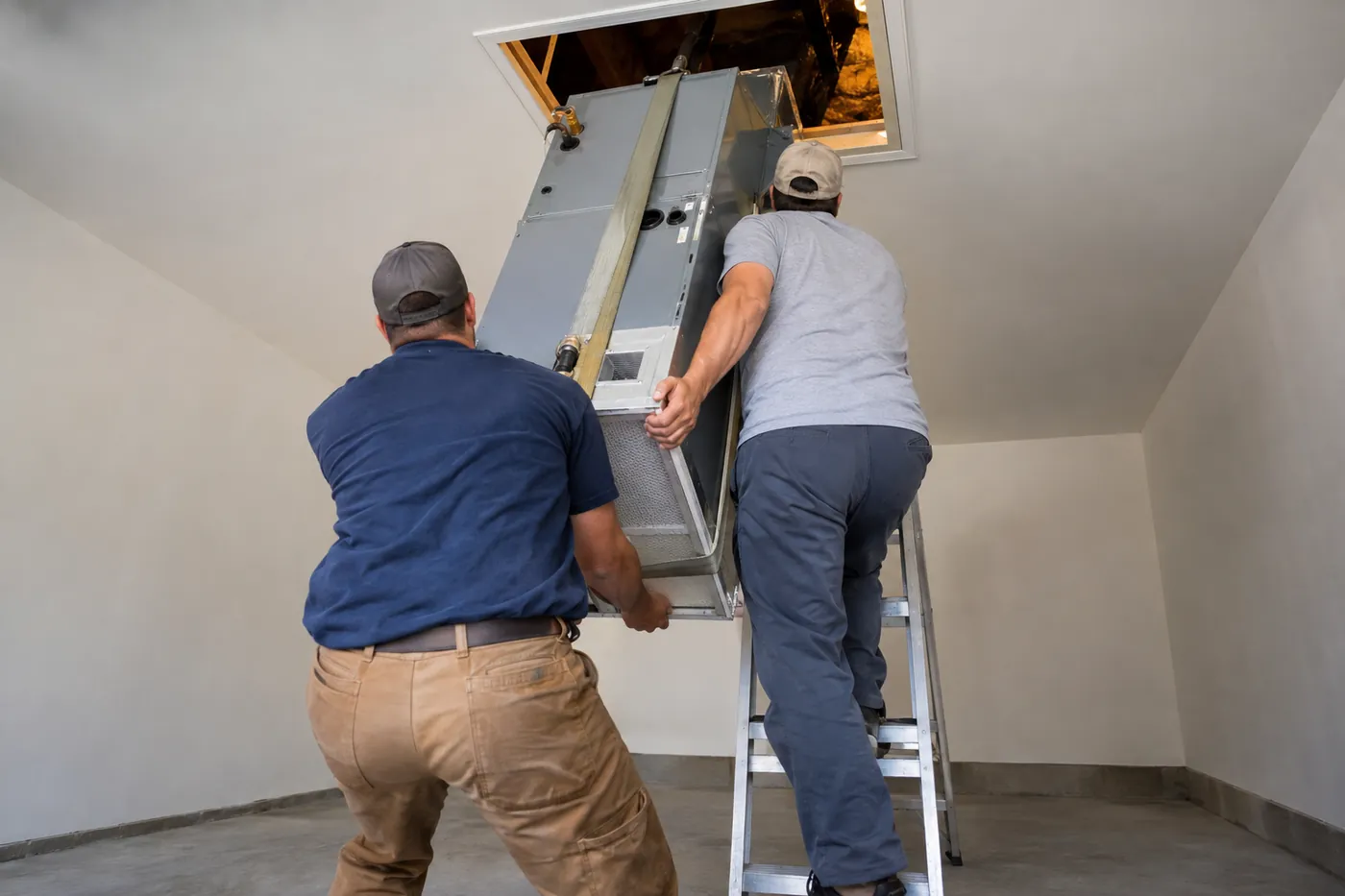 Technicians lifting a new indoor unit into the attic