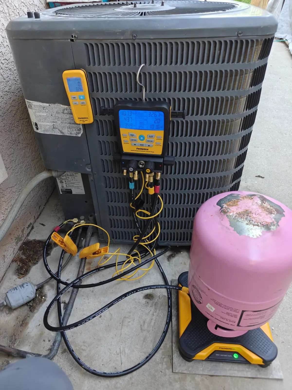 Refrigerant gauges connected to an outdoor AC condenser during a Pro Fix service call